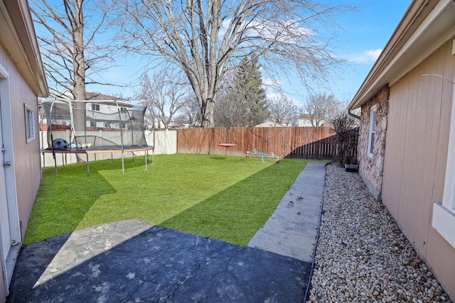 view of yard featuring a patio, a trampoline, and a fenced backyard