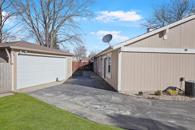 view of home's exterior with an outbuilding, cooling unit, fence, and a detached garage