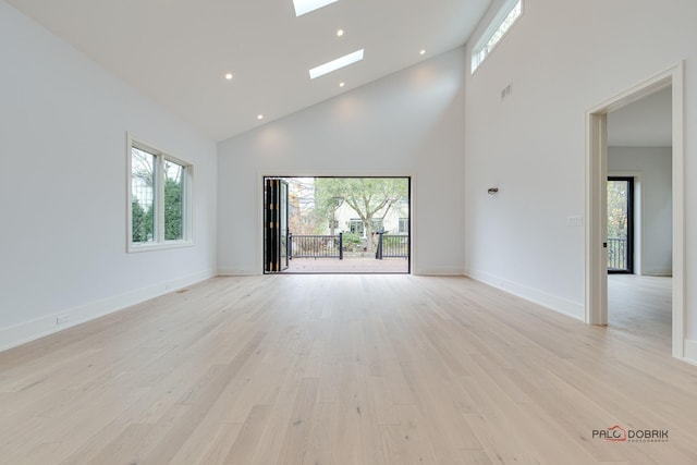 empty room with a healthy amount of sunlight, a skylight, and light wood finished floors