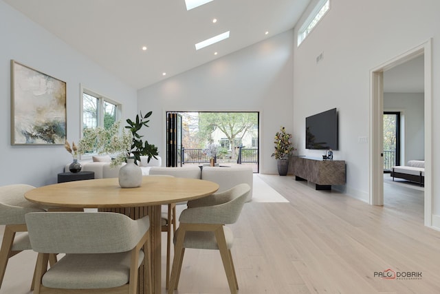 dining area featuring plenty of natural light, light wood-style flooring, and a skylight