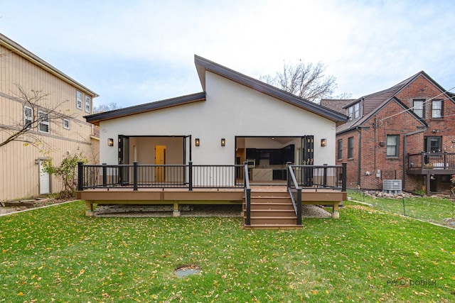 back of property featuring a deck, a yard, an attached garage, and stucco siding