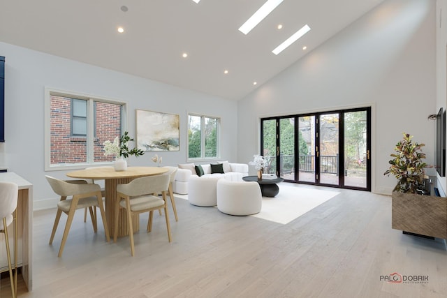 dining space featuring recessed lighting, light wood-style flooring, high vaulted ceiling, and a skylight