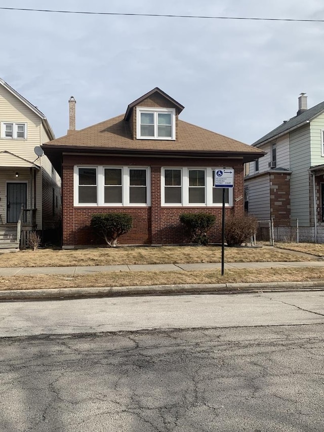 bungalow featuring brick siding