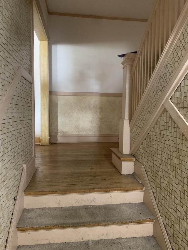 stairs featuring ornamental molding, wood finished floors, and wallpapered walls