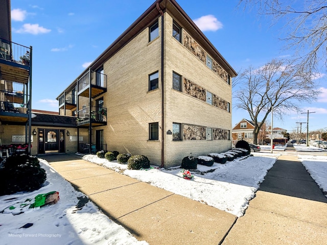 view of snow covered exterior with brick siding