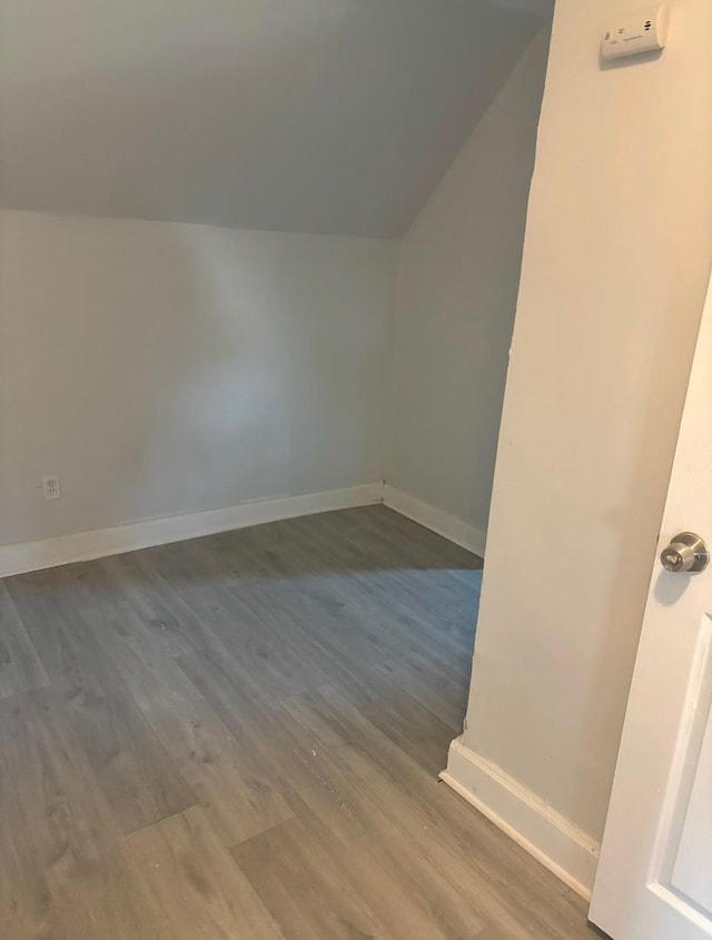 additional living space with baseboards, vaulted ceiling, and wood finished floors