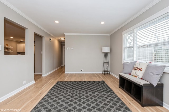 living area featuring light wood-style floors, baseboards, and crown molding