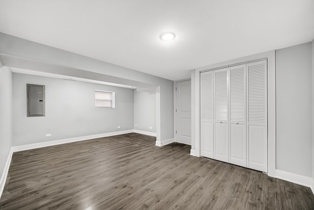 unfurnished bedroom featuring a closet, electric panel, baseboards, and dark wood-style flooring