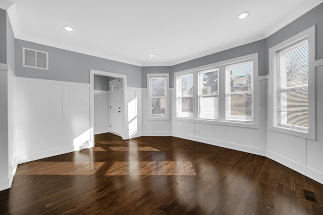 unfurnished room with crown molding, dark wood-style flooring, visible vents, and a decorative wall