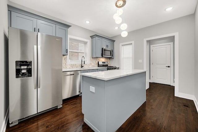 kitchen featuring stainless steel appliances, dark wood-type flooring, hanging light fixtures, light countertops, and a center island