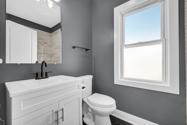 bathroom featuring a wealth of natural light, toilet, vanity, and baseboards