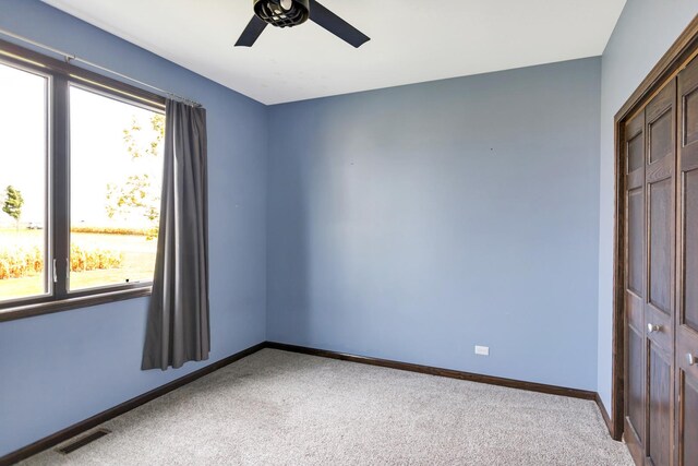 unfurnished room featuring a ceiling fan, light colored carpet, visible vents, and baseboards