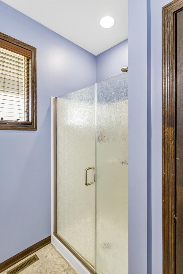 bathroom with a stall shower, visible vents, and baseboards