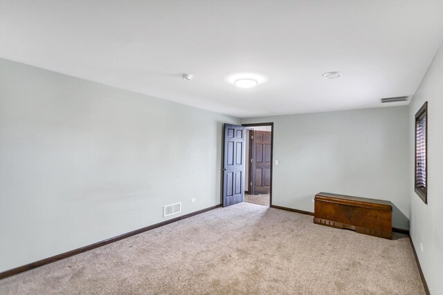 empty room featuring baseboards, visible vents, and light colored carpet