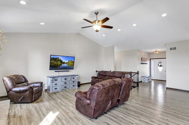 living area with light wood-style floors, visible vents, vaulted ceiling, and baseboards