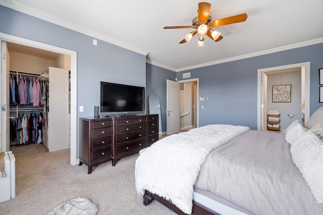 carpeted bedroom with ceiling fan, crown molding, a walk in closet, and a closet