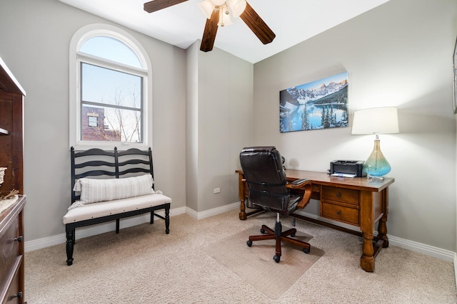 carpeted office space featuring a ceiling fan and baseboards