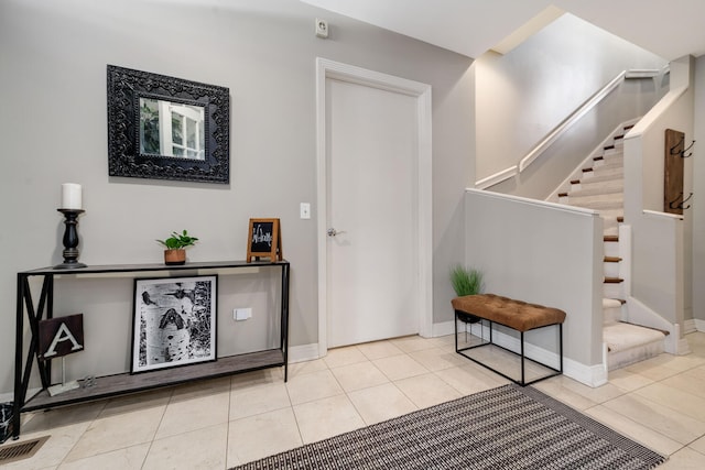 foyer with stairs, visible vents, baseboards, and tile patterned floors