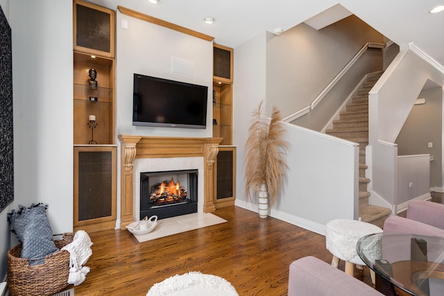 living area featuring built in shelves, recessed lighting, a fireplace, wood finished floors, and stairway