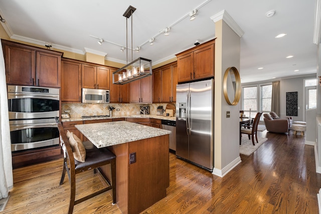 kitchen with tasteful backsplash, appliances with stainless steel finishes, crown molding, and a center island