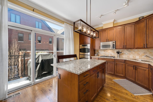 kitchen with visible vents, wood finished floors, stainless steel appliances, crown molding, and a sink