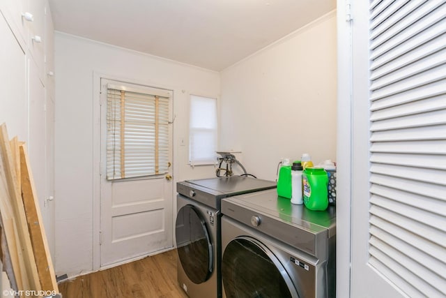 laundry room featuring ornamental molding, laundry area, washing machine and clothes dryer, and wood finished floors