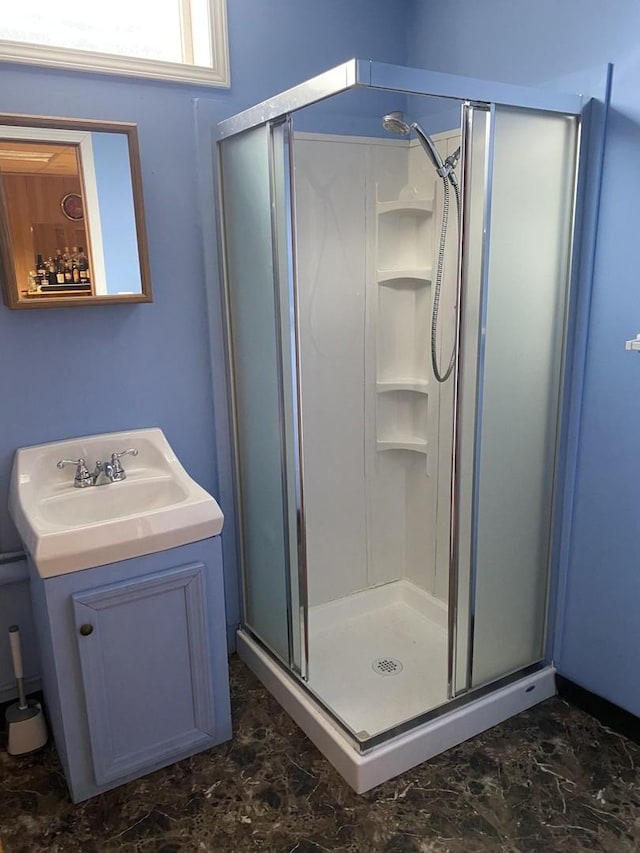 bathroom with marble finish floor, a sink, and a shower stall