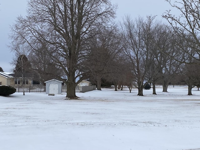 yard covered in snow with a shed and fence