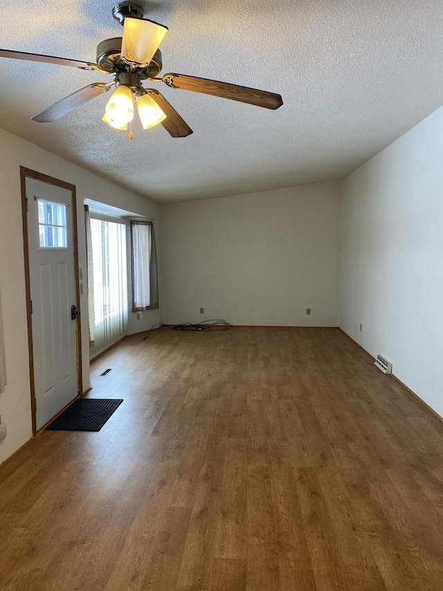 entrance foyer featuring a textured ceiling, wood finished floors, visible vents, and a ceiling fan