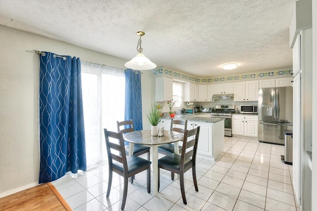 dining area featuring light tile patterned floors, a textured ceiling, and baseboards