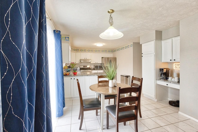 dining area featuring light tile patterned flooring and a textured ceiling