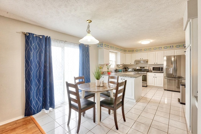 dining area with a textured ceiling, light tile patterned flooring, and baseboards