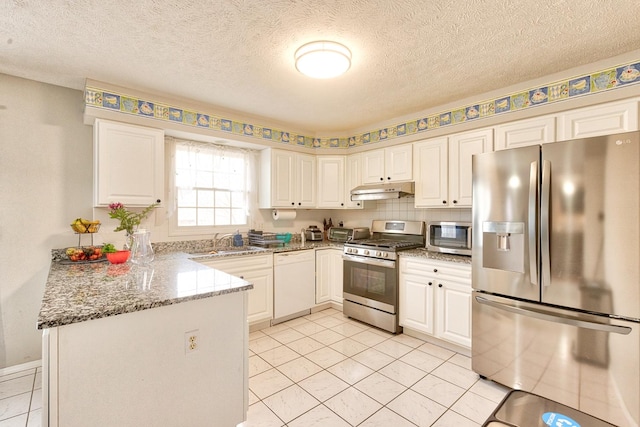 kitchen featuring under cabinet range hood, stainless steel appliances, a peninsula, a sink, and white cabinets