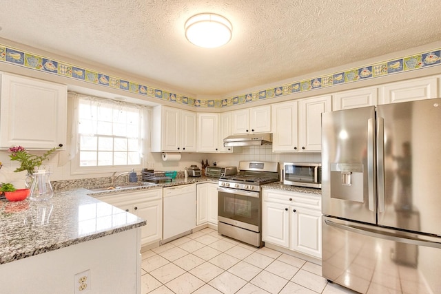 kitchen featuring light stone counters, under cabinet range hood, stainless steel appliances, a sink, and white cabinetry