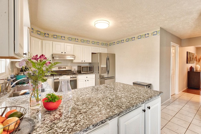 kitchen featuring white cabinetry, stainless steel appliances, a sink, and dark stone counters