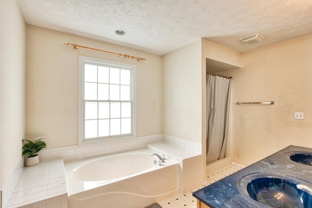 bathroom featuring a garden tub, double vanity, visible vents, a sink, and a textured ceiling