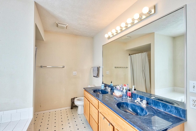 bathroom with a sink, a textured ceiling, toilet, and tile patterned floors