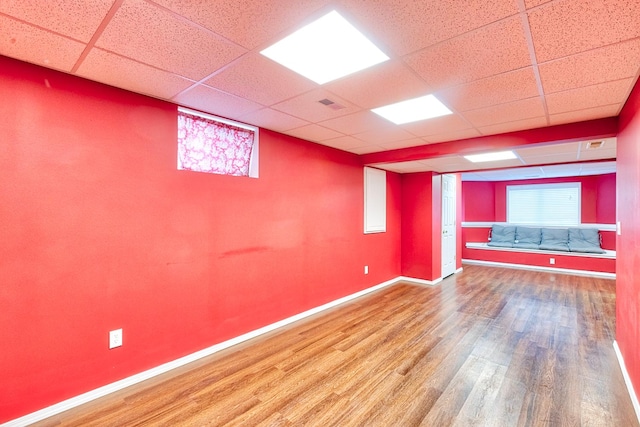 interior space with visible vents, a drop ceiling, baseboards, and wood finished floors