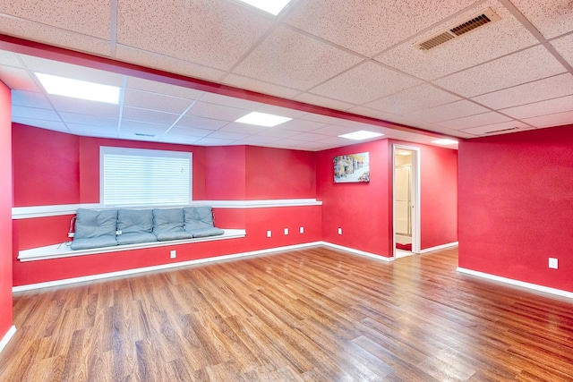 unfurnished room with a drop ceiling, wood finished floors, visible vents, and baseboards