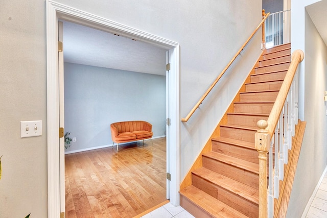 stairs featuring wood finished floors and baseboards