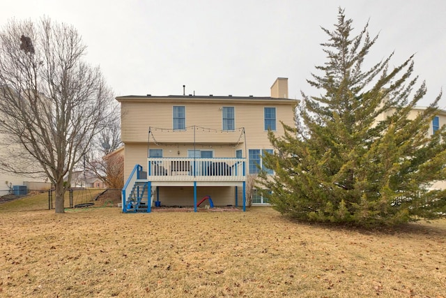 back of house featuring a yard, a chimney, fence, a deck, and stairs