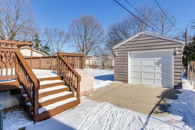 yard layered in snow featuring a wooden deck, a detached garage, stairway, and an outbuilding