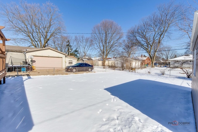 snowy yard featuring a garage and fence