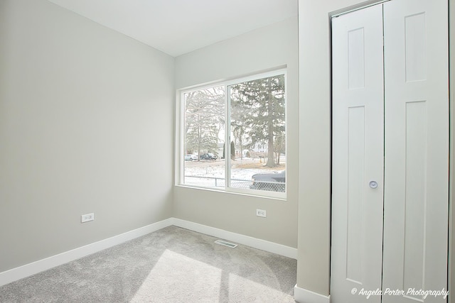 spare room featuring carpet flooring, visible vents, and baseboards