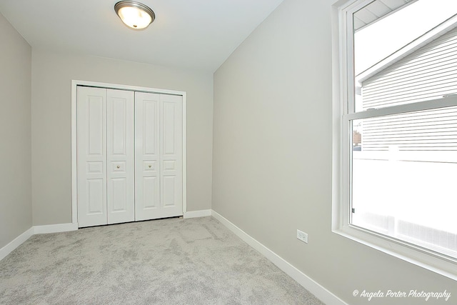 unfurnished bedroom featuring carpet, baseboards, and a closet