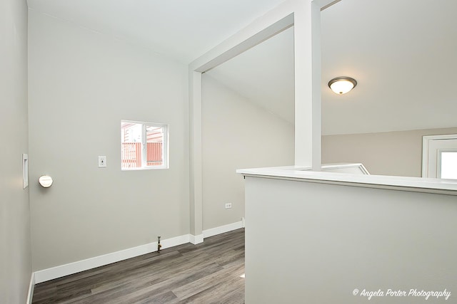 unfurnished room featuring vaulted ceiling, baseboards, and wood finished floors