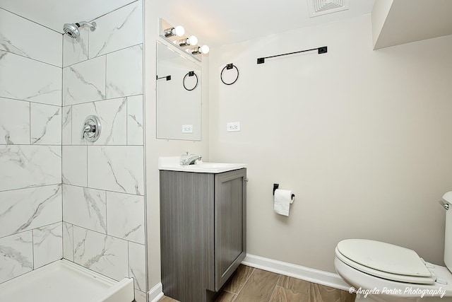 bathroom with visible vents, vanity, a shower stall, and toilet