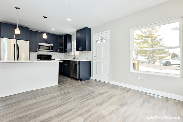 kitchen with light countertops, visible vents, decorative backsplash, appliances with stainless steel finishes, and light wood-style floors