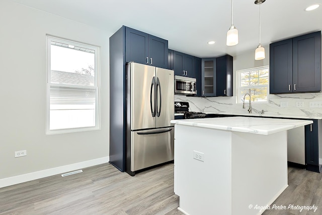 kitchen featuring visible vents, backsplash, appliances with stainless steel finishes, light wood-style floors, and glass insert cabinets