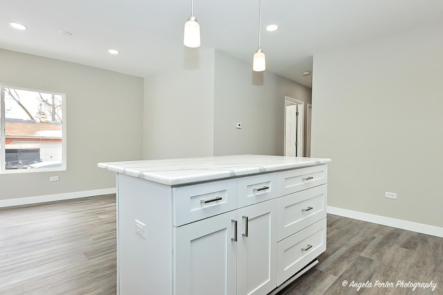 kitchen featuring baseboards, light stone counters, hanging light fixtures, light wood-type flooring, and recessed lighting